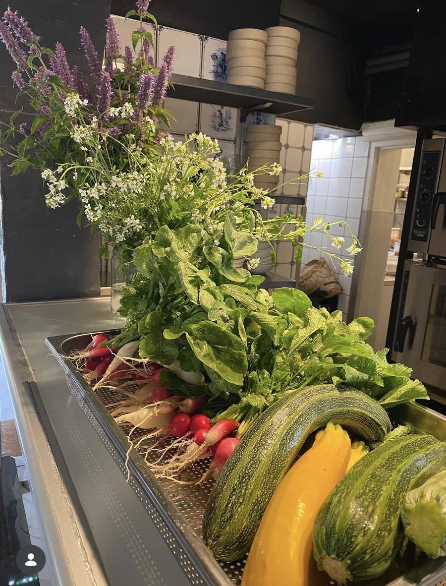 Radiser, squash og vilde blomster på køkkenbordet på Beghuset