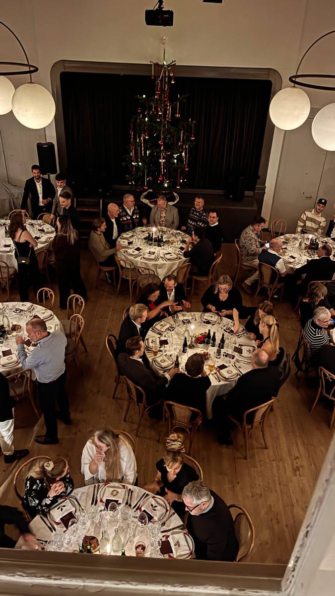 Julefrokost i Beghusets Teatersal set ovenfra med runde borde og pyntet juletræ